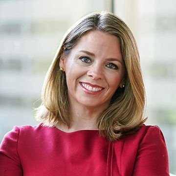 Portrait of a smiling woman with shoulder-length blonde hair in a red blouse, facing the camera.